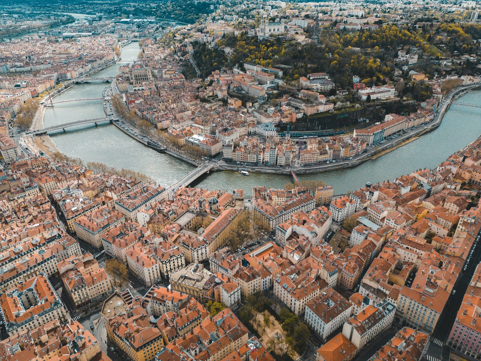 Vue aérienne de Lyon : la Saône serpente entre les toits de tuiles de la Presqu’île et du Vieux Lyon.